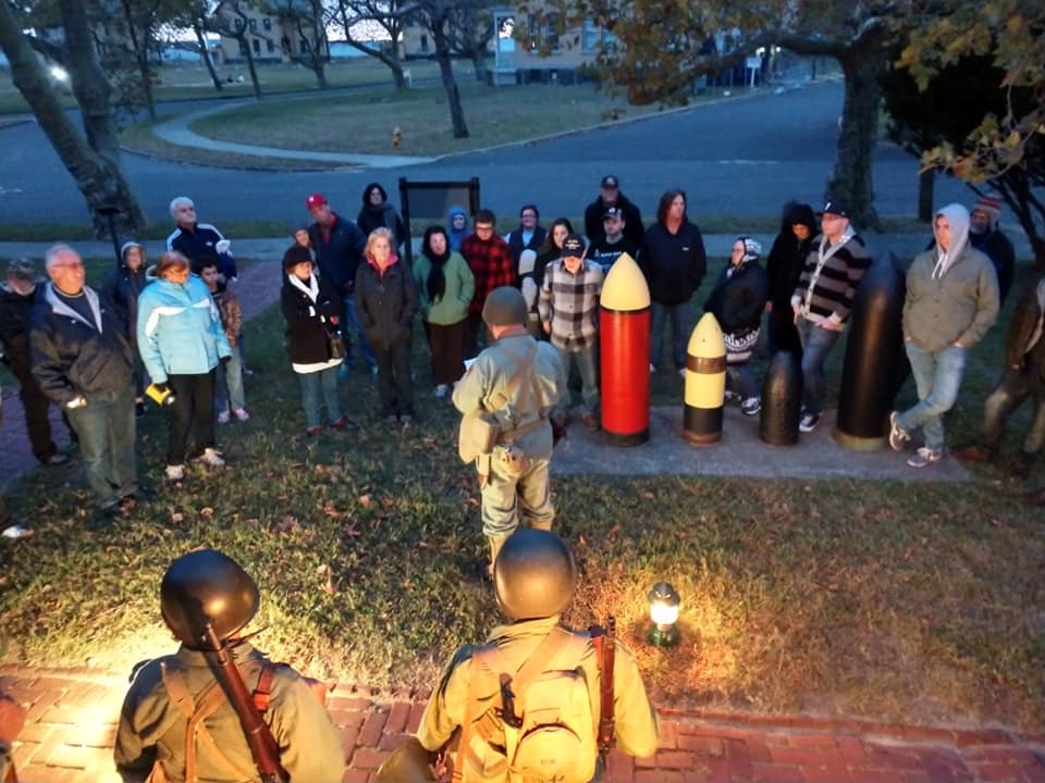 Historian in uniform speaking to a group of the public by lantern light